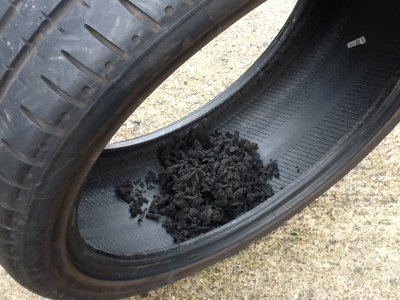 Accumulated rubber dust and shredded debris inside a tyre that has been driven flat, evidence of internal delamination.