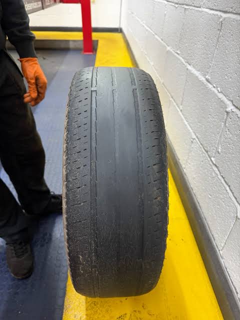 Top-down view of a bald tyre worn almost smooth across the centre, with only shallow grooves remaining at the edges.