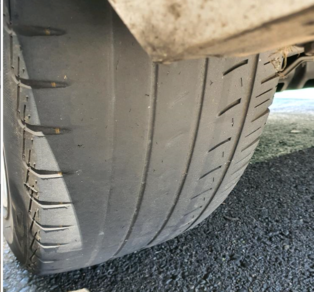 Angled close-up of a tyre with a slick bald centre tread while the outer shoulder still holds some groove pattern.