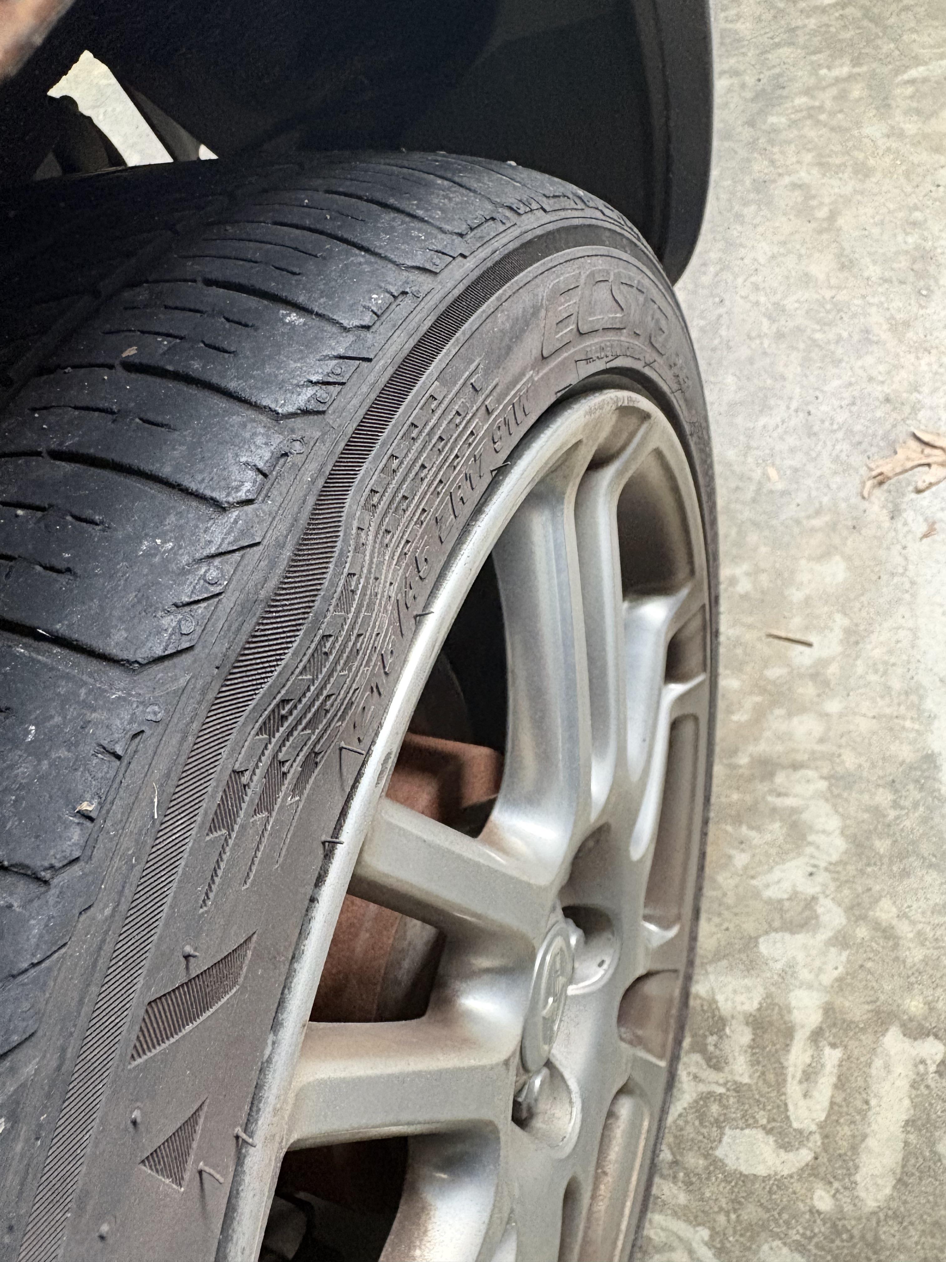 A tyre sidewall with a clear indentation and wavy distortion indicating internal structural failure.