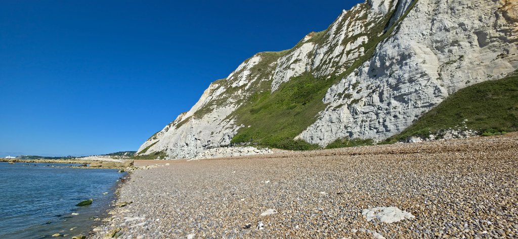 Open grassland path with the cliffs rising alongside