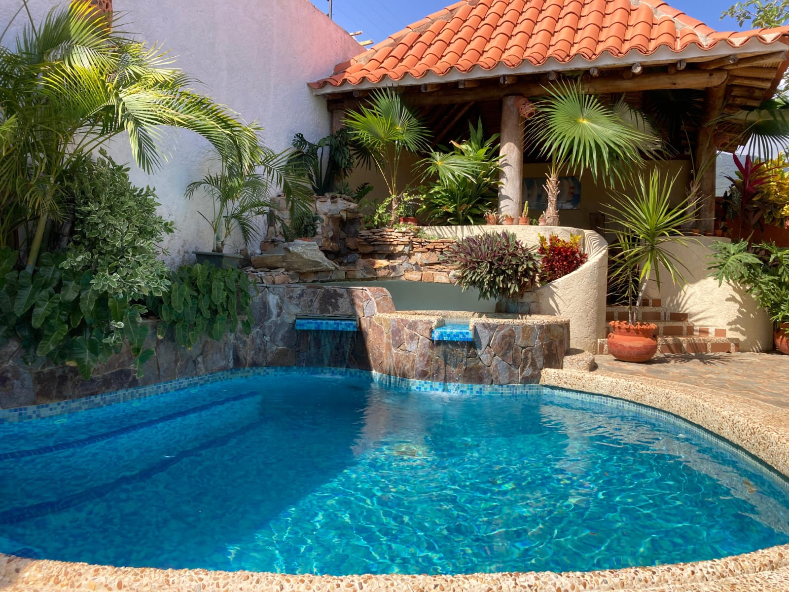 Piscina circular con fuente y vegetación tropical en Molino's Village