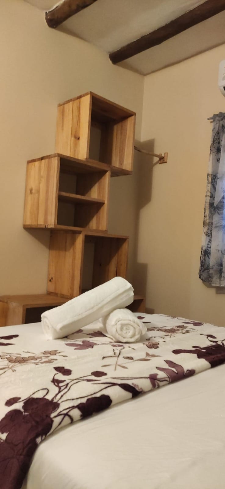 Detalle de repisas de madera y cama con textiles artesanales