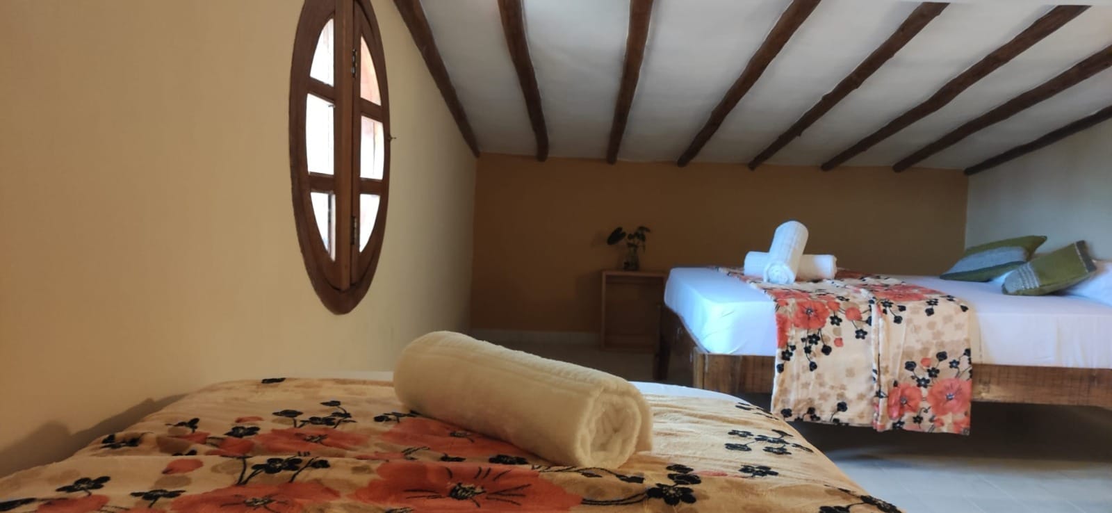 Habitación con ventana ovalada y vigas de madera