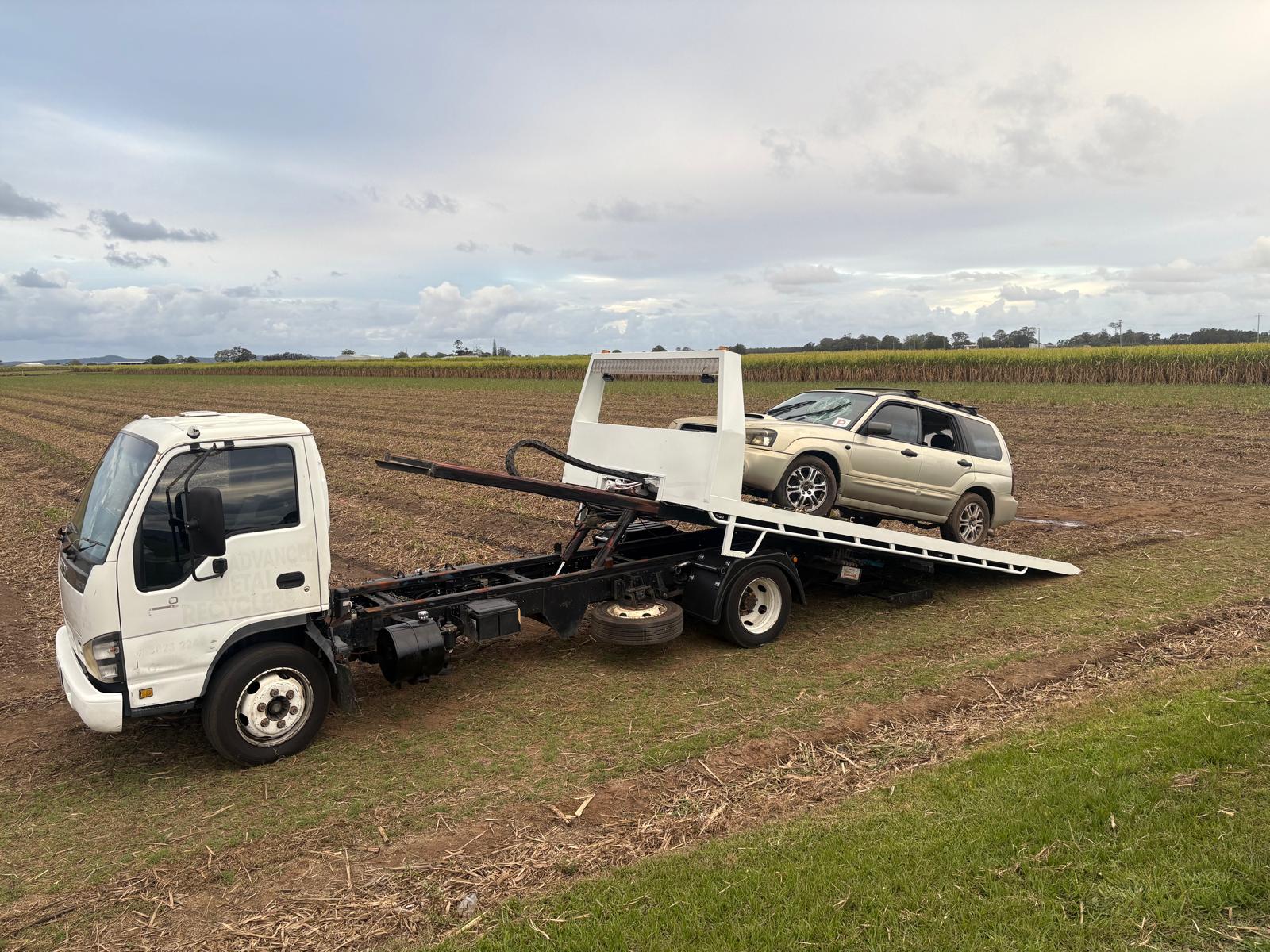 Tilt tray tow truck winching a recovered Subaru Forester out of a paddock