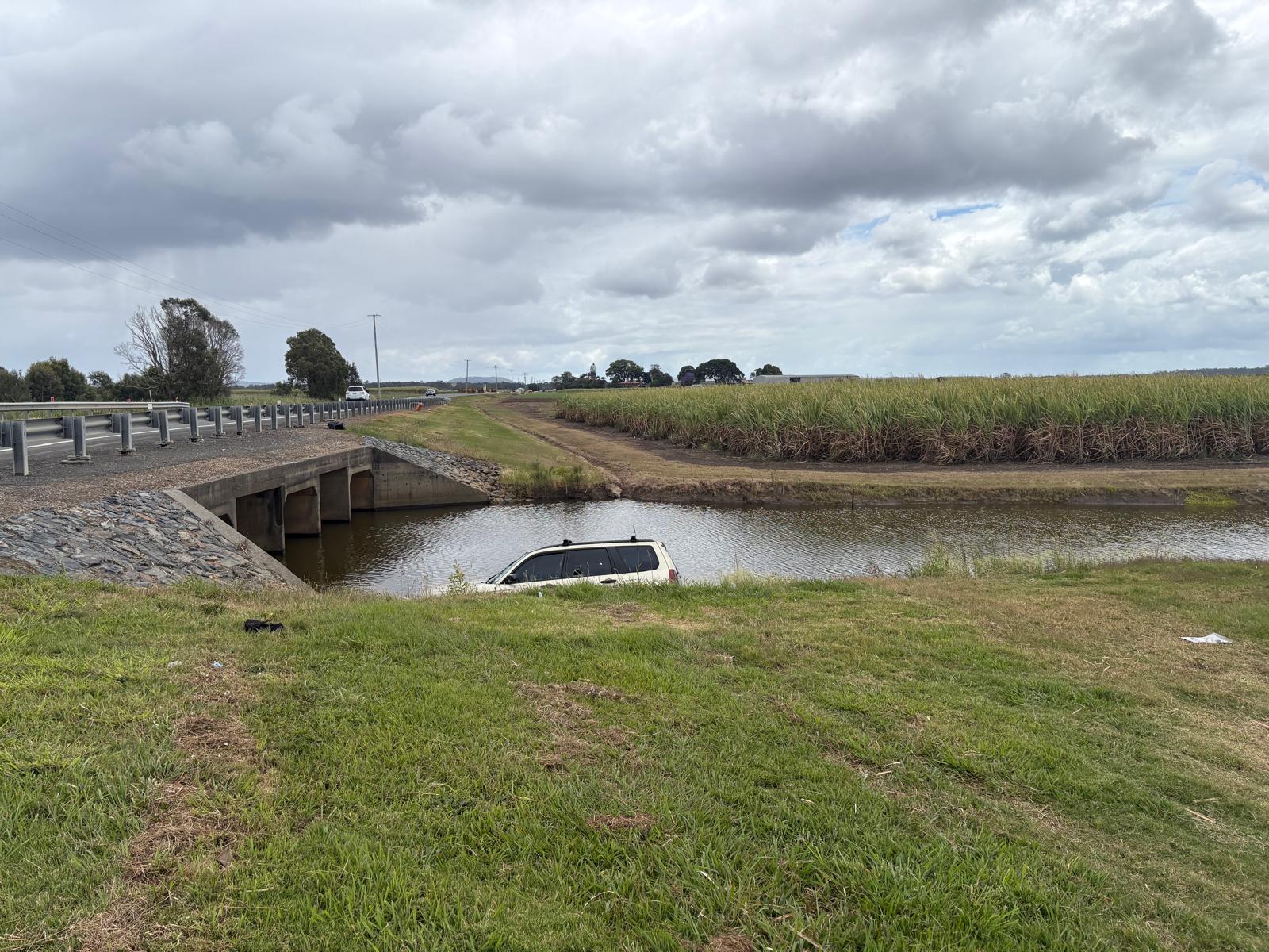 Subaru Forester submerged in a creek beside a rural bridge awaiting recovery