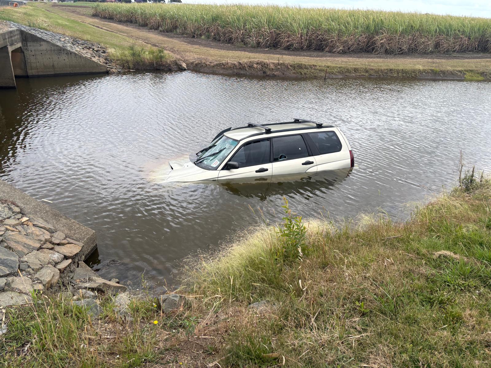 Flood damaged car half submerged in a Northern Rivers waterway