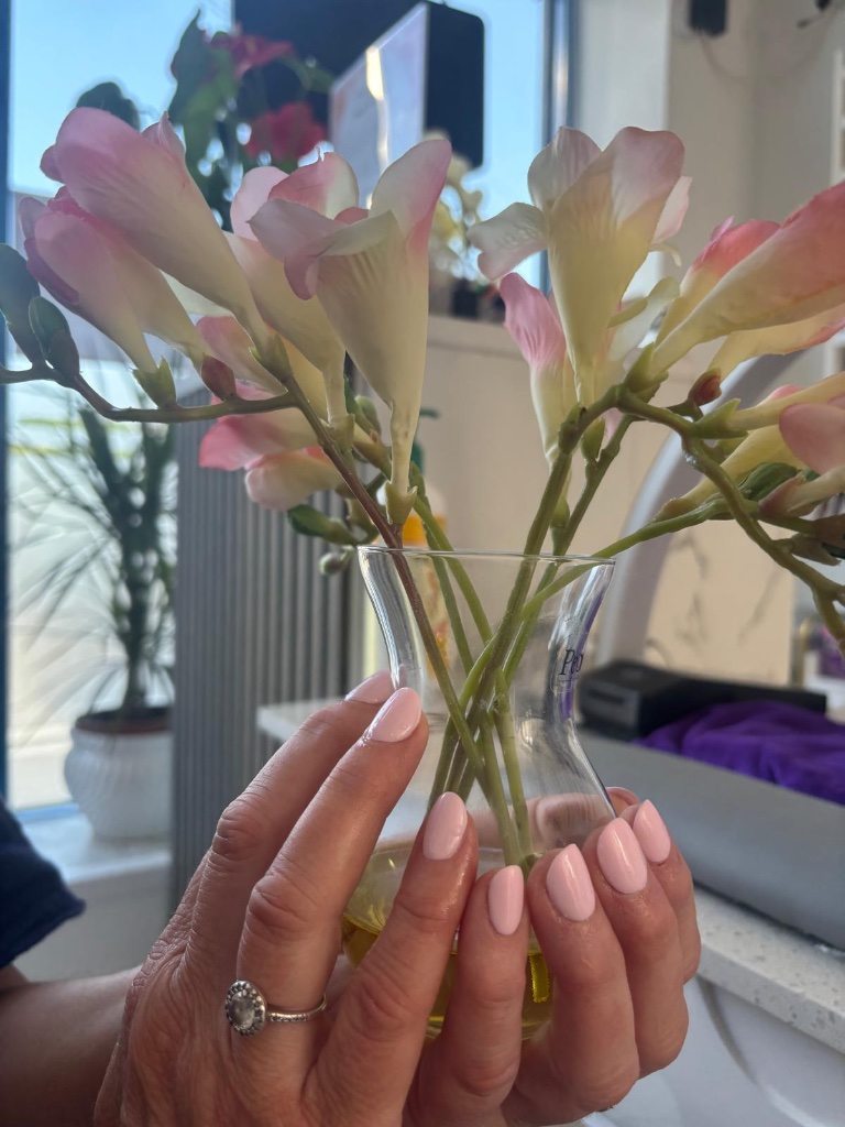 Light pink nails holding flowers