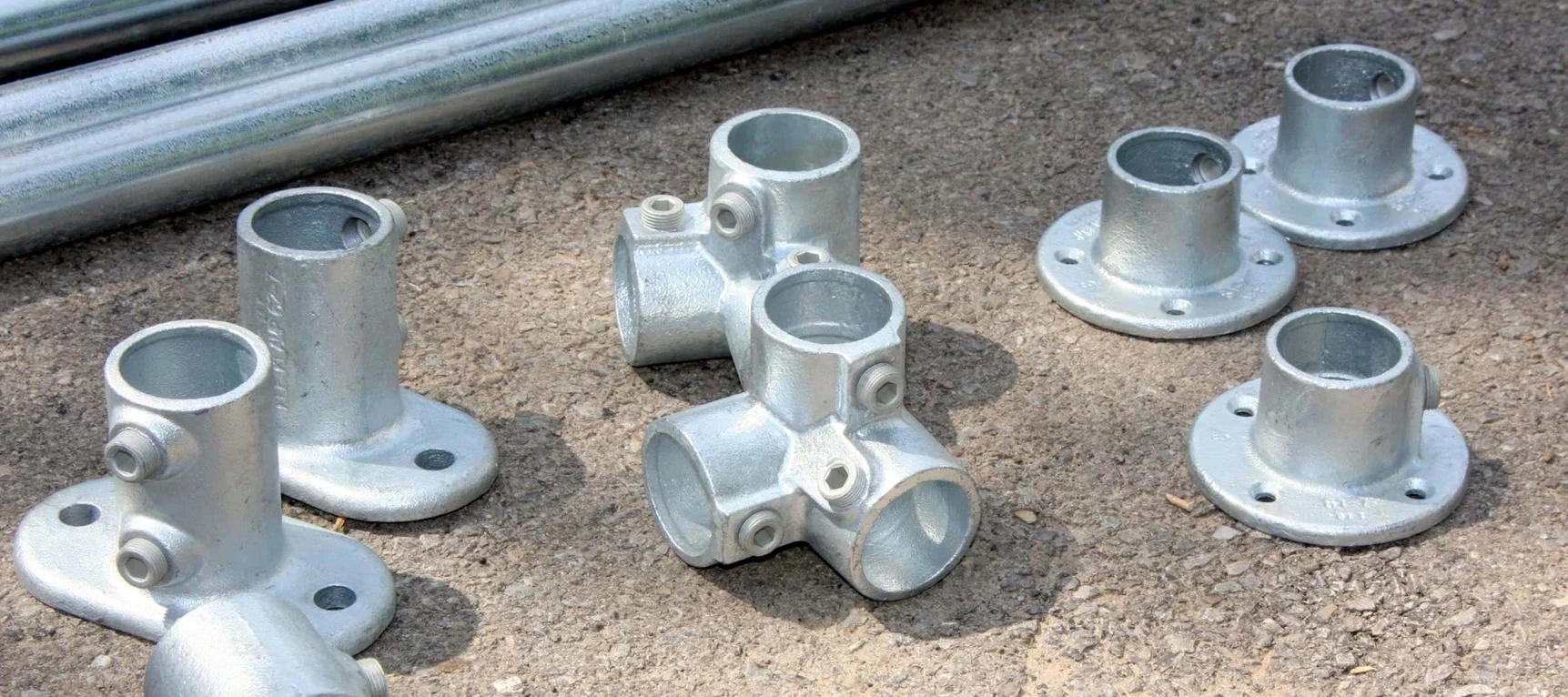 Top-down view of industrial pipe fittings arranged in a grid formation on concrete surface