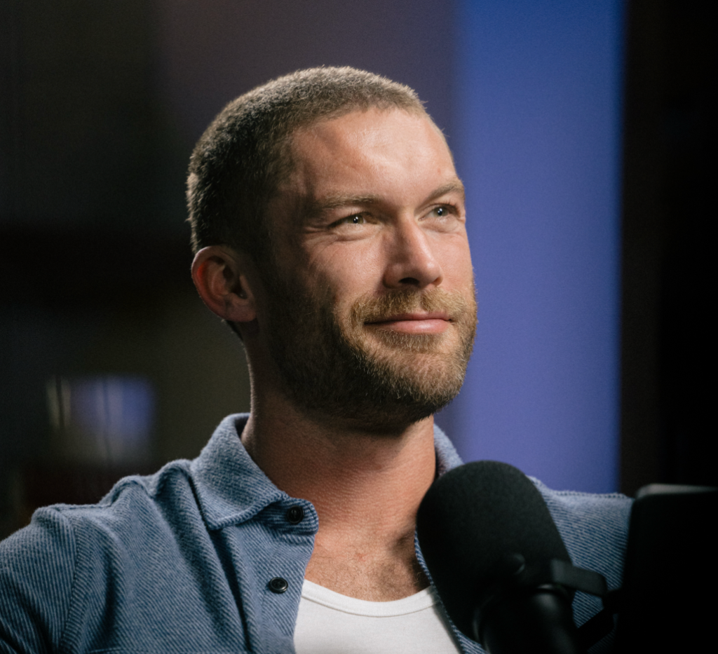 Man in a blue shirt beside a studio microphone