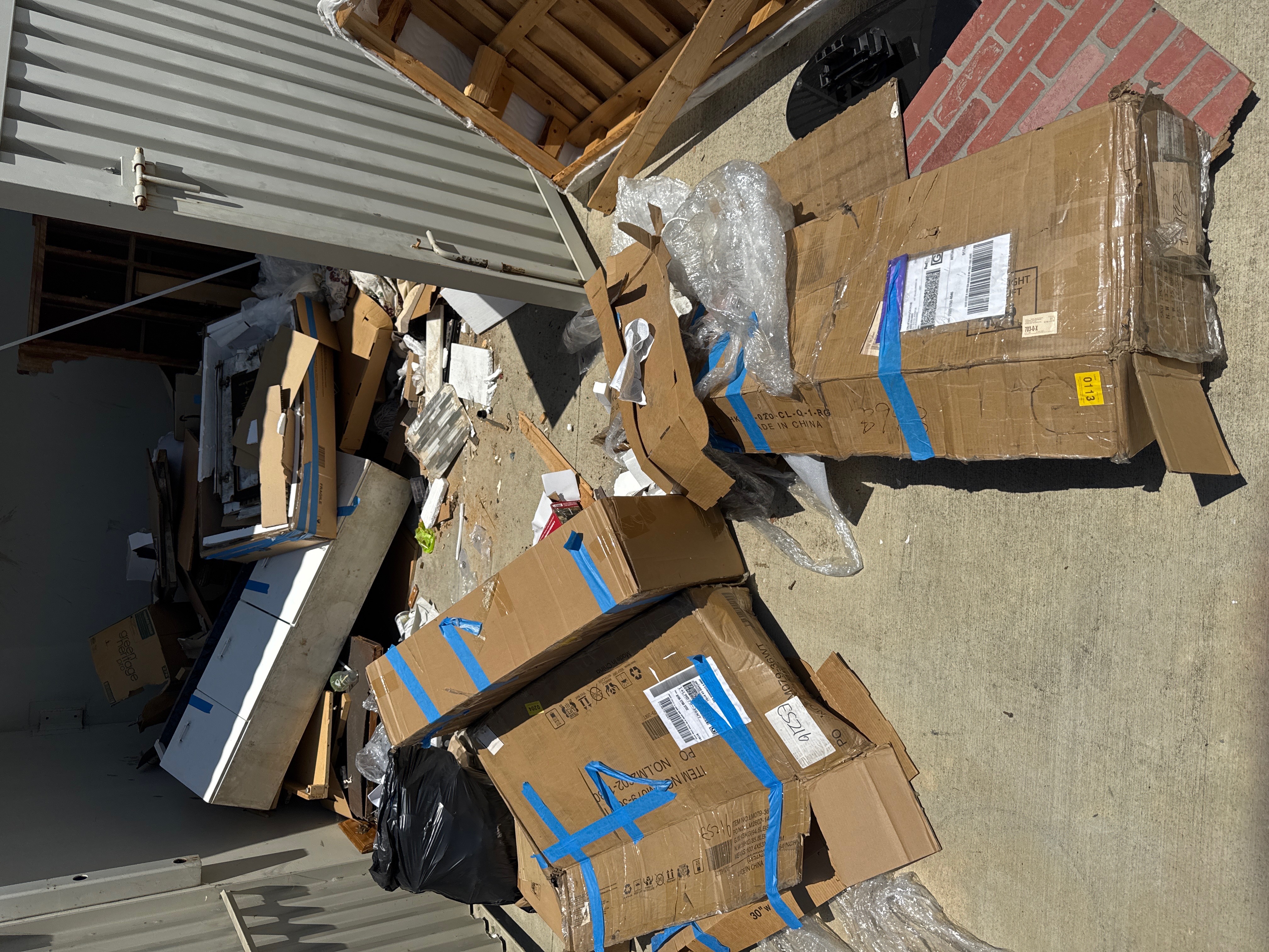 Dumped cardboard boxes and debris against a metal wall - before cleanup