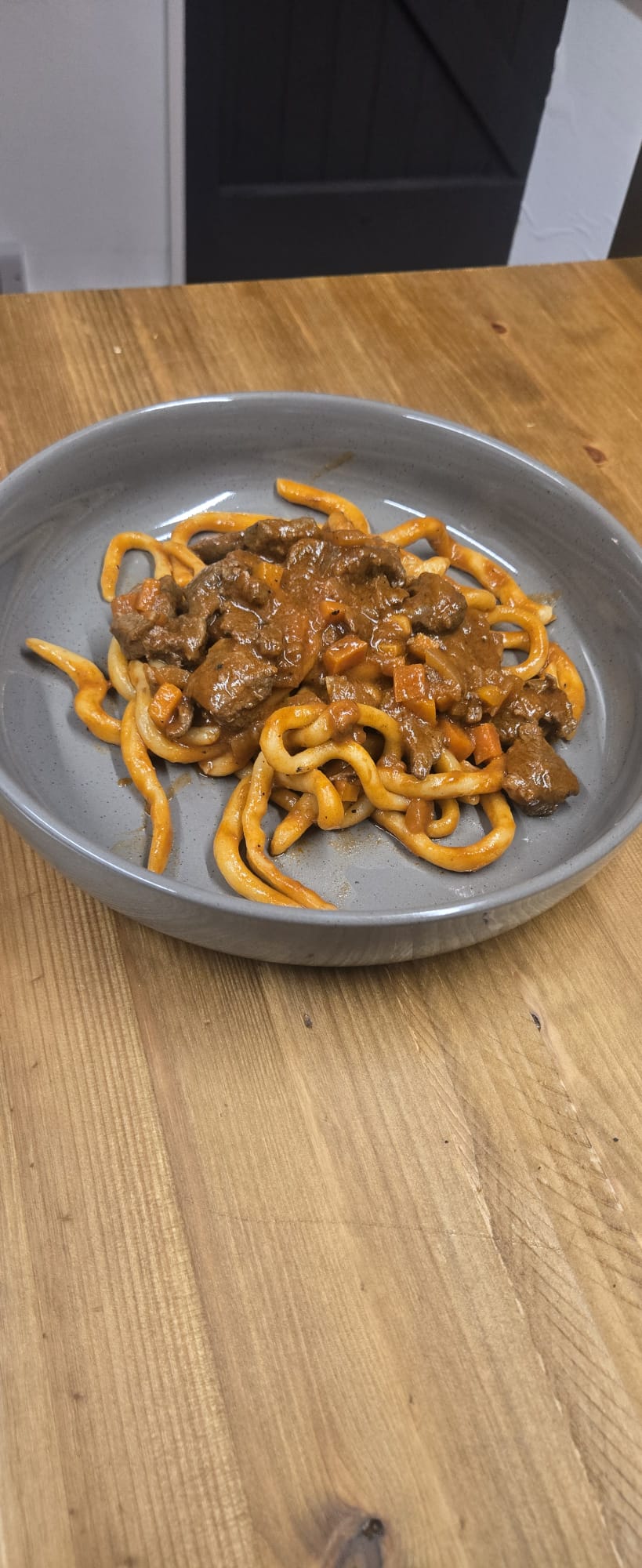 Pici al ragù on wooden table