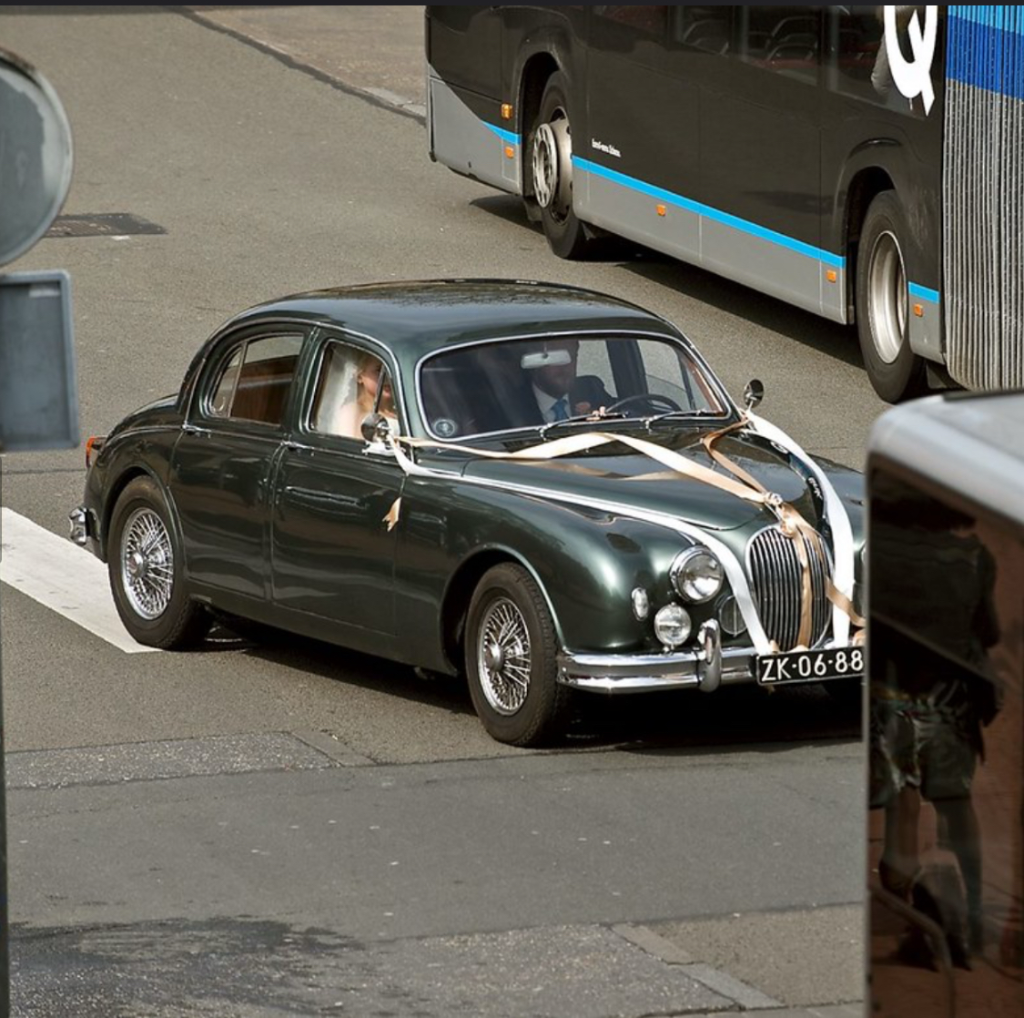 Bruidspaar bij een klassieke auto tijdens hun bruiloft