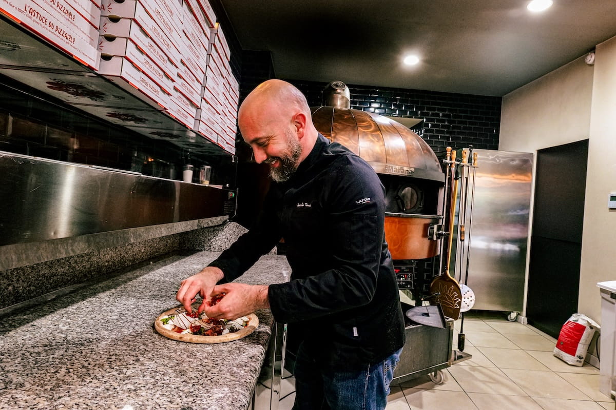 Jordan Tomas préparant une pizza dans sa cuisine