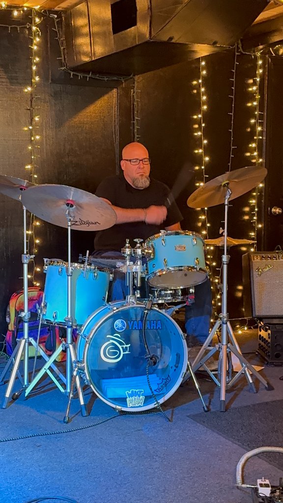 Drummer on stage with blue kit and string lights