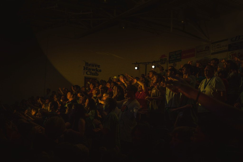 Camp audience gathered in a gymnasium under stage light