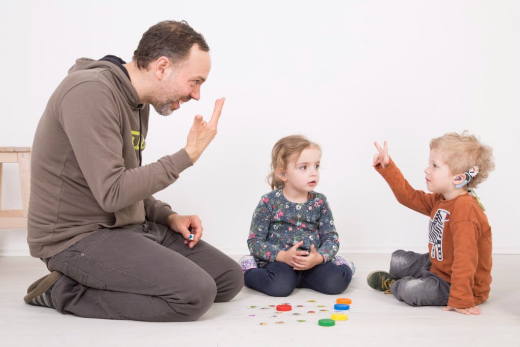 Vater kommuniziert mit Kindern in Gebärdensprache