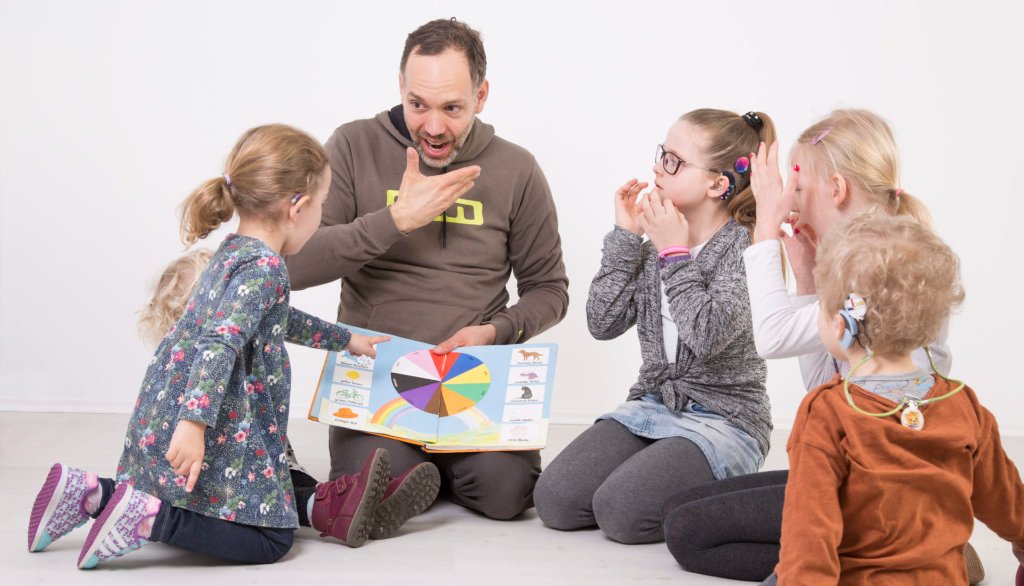 Mann unterrichtet Kinder in Gebärdensprache
