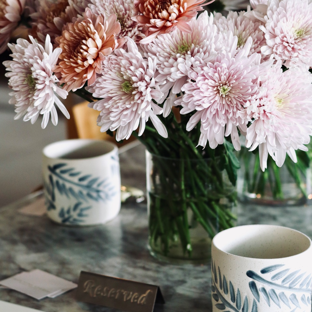 Reserved table with pink chrysanthemums and ceramic mugs