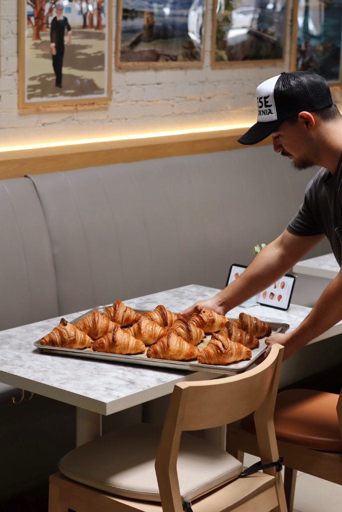 Baker placing fresh croissants on the table