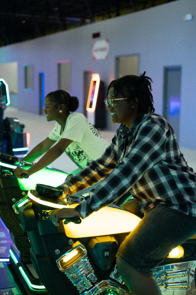 Two people racing on motorcycle-style arcade games at Lululand Adventure Park