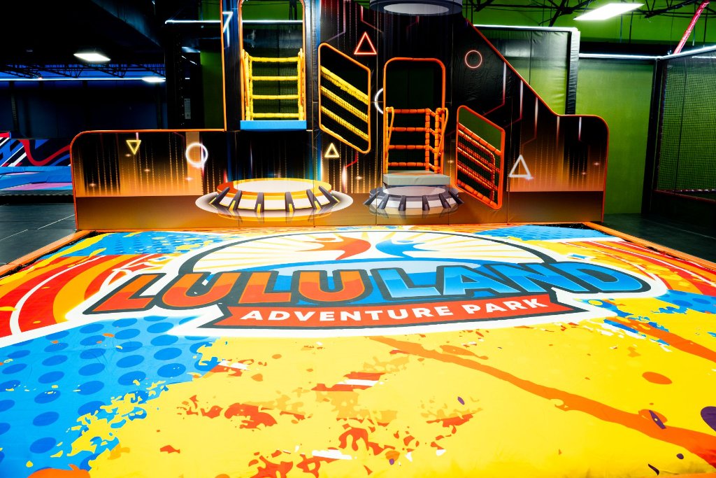 Lululand Adventure Park branded trampoline zone with colorful logo mat and climbing platforms