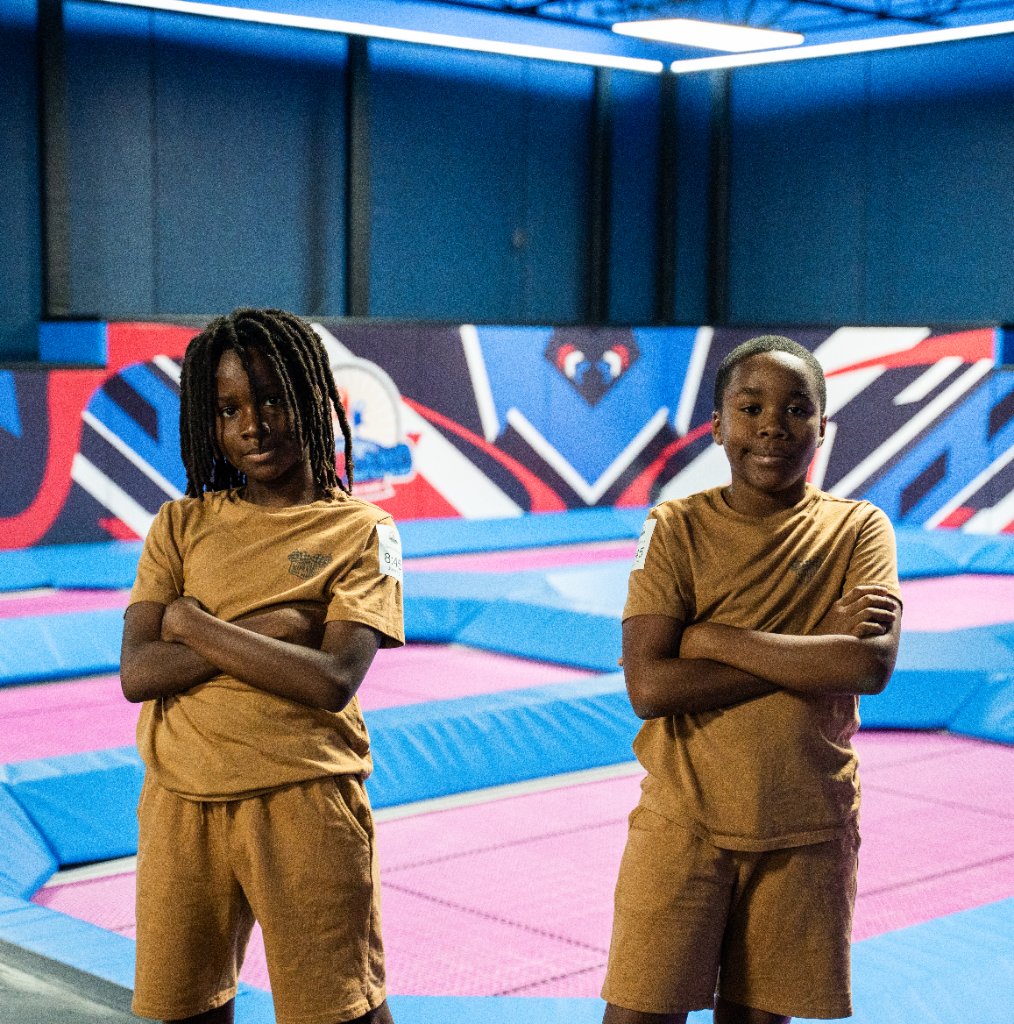 Two children standing confidently on a colorful trampoline at Lululand Adventure Park
