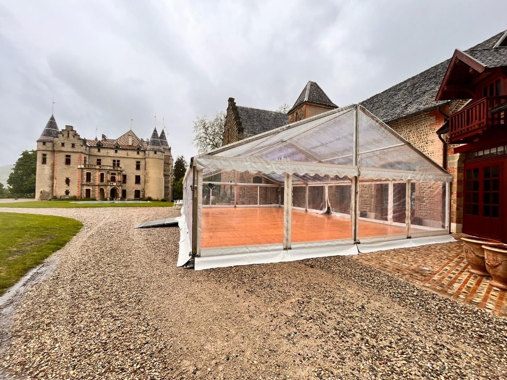 Chapiteau cristal avec plancher bois devant un château