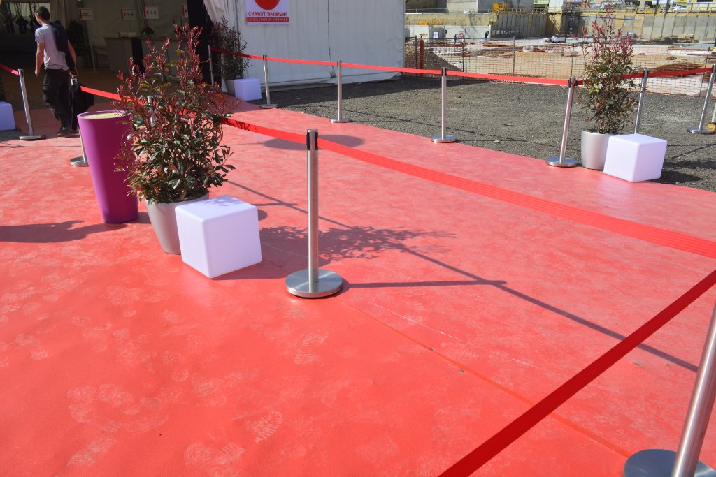 Moquette rouge déroulée avec poteaux de guidage pour événement