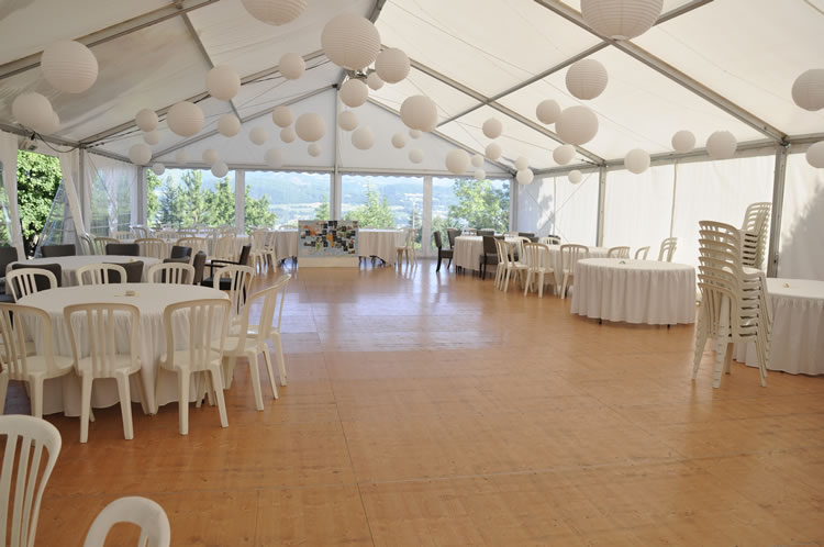 Intérieur de chapiteau avec lampions et tables rondes pour réception