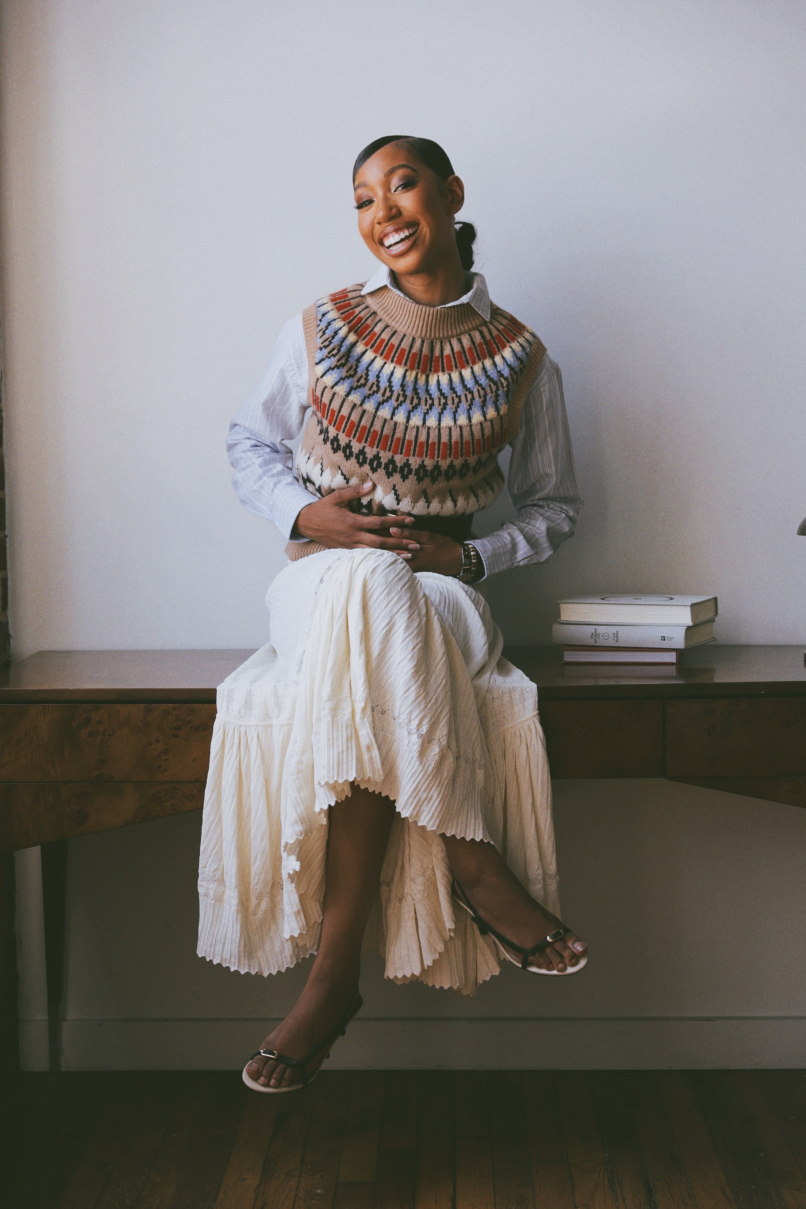 Nina, the stylist, seated on a wooden desk