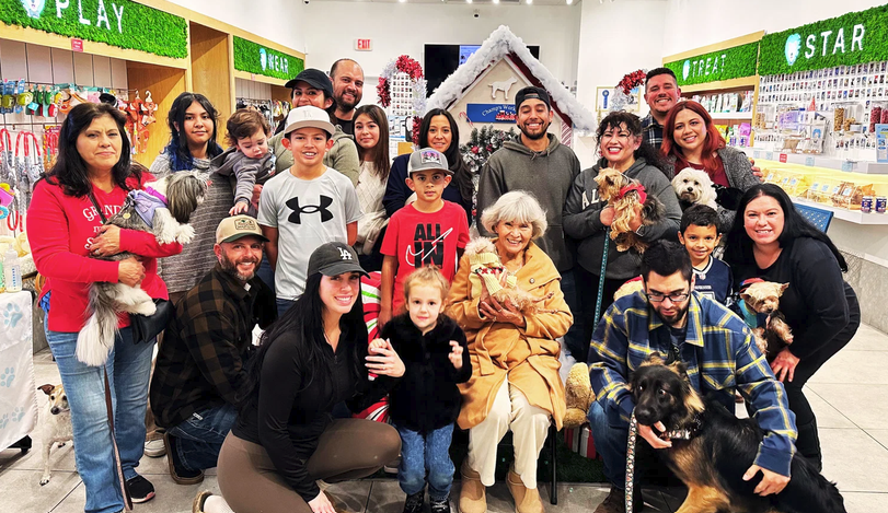 A large group of Puptqe guests posing with their dogs inside the store