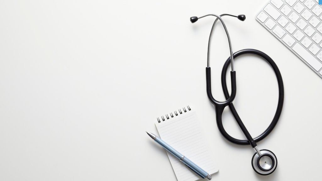 Stethoscope, keyboard, and notebook on a clean background