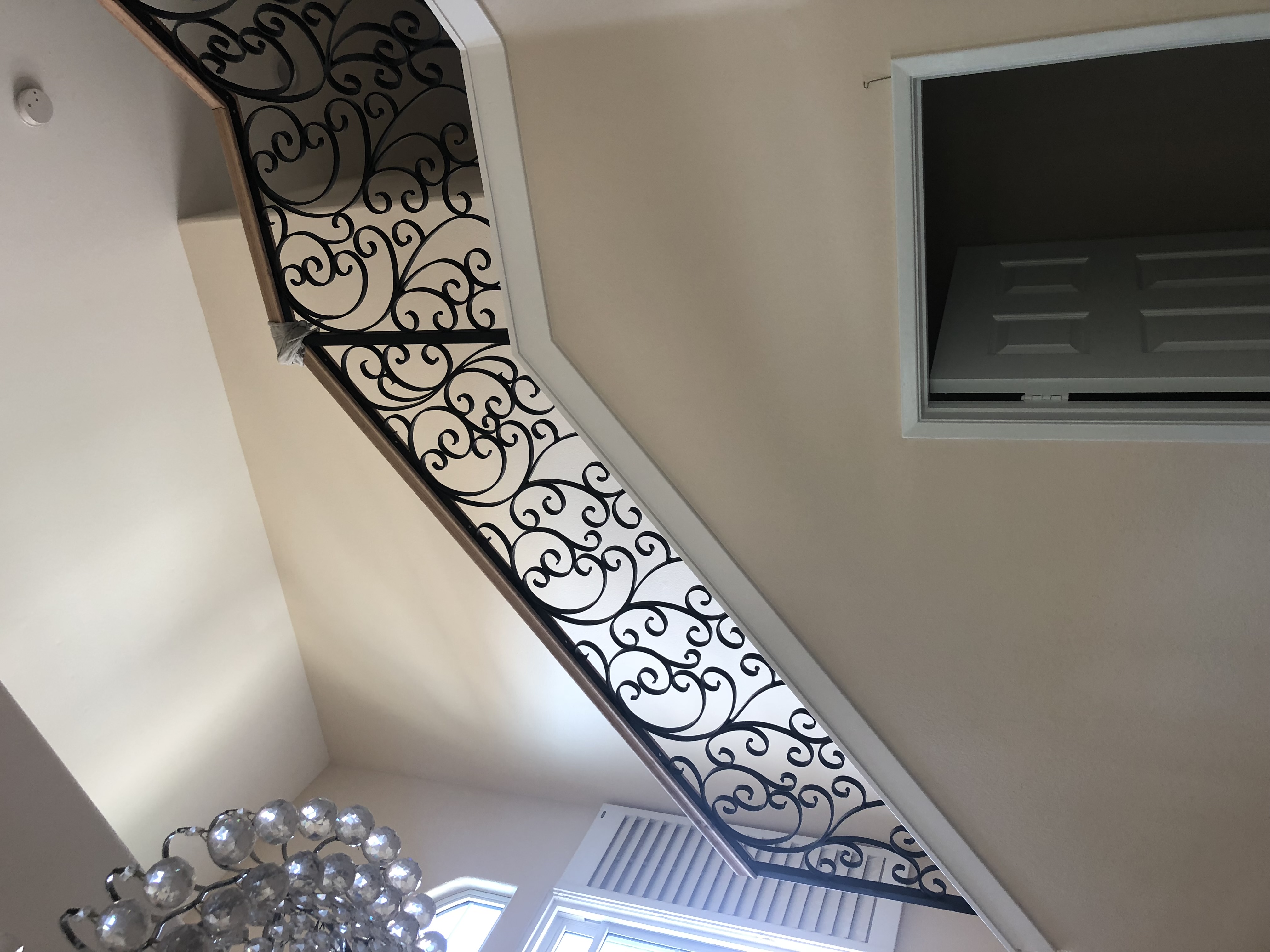 Scrollwork Curved Staircase Railing Under Chandelier