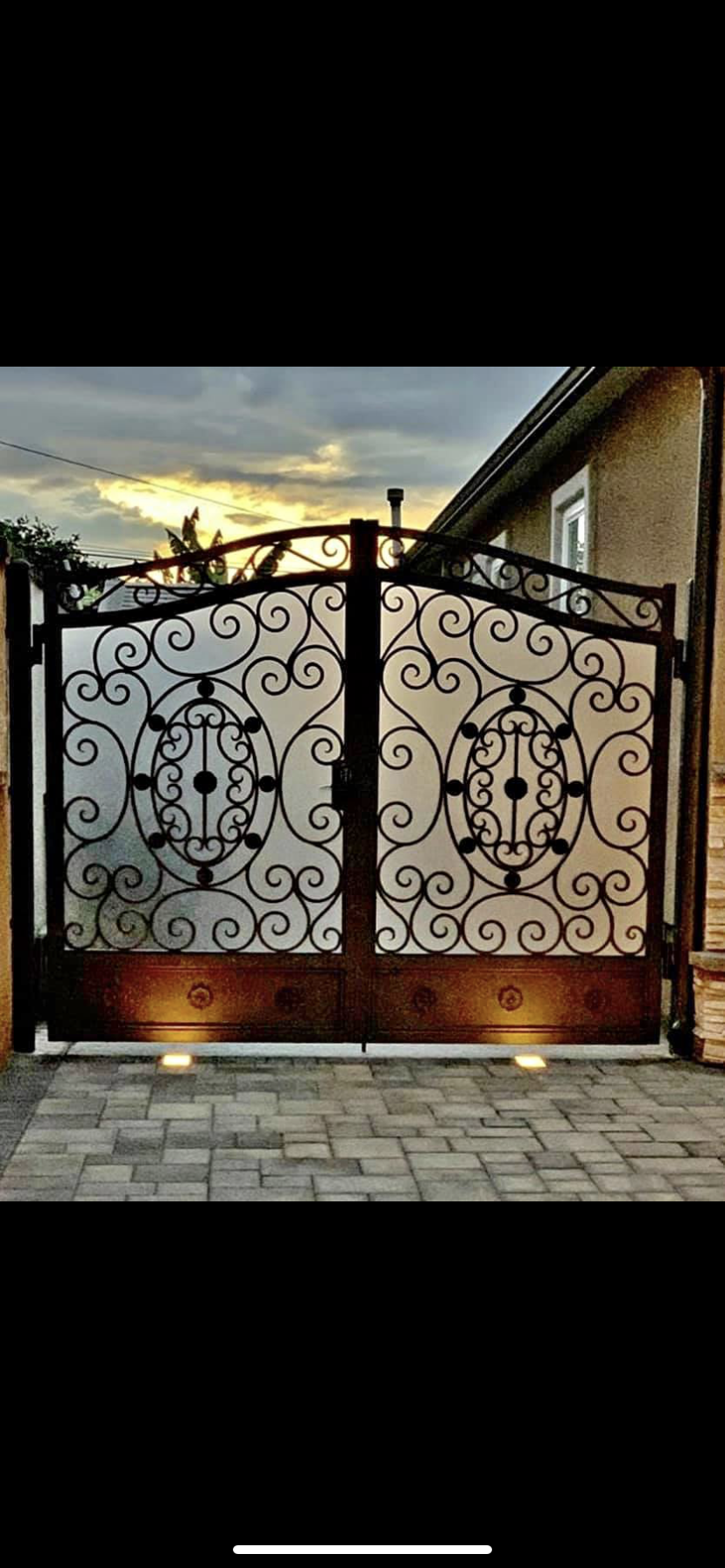Ornate Scrollwork Driveway Gate at Dusk