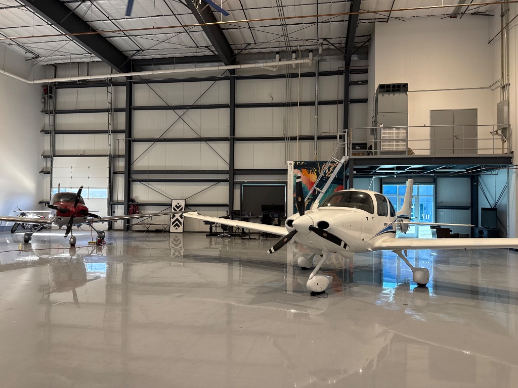 Two aircraft parked inside a spacious hangar at Legacy Aviation