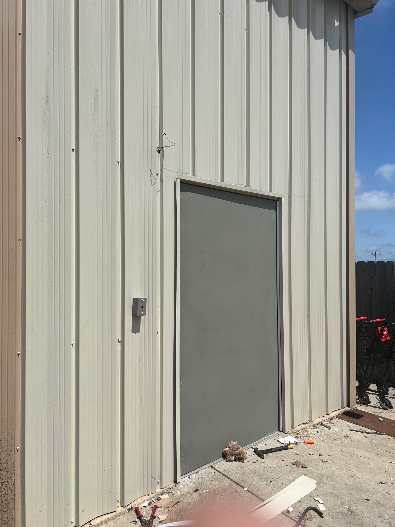 Real TNT Roofing commercial project: completed vertical metal siding wall with steel entry door on a dollar store exterior