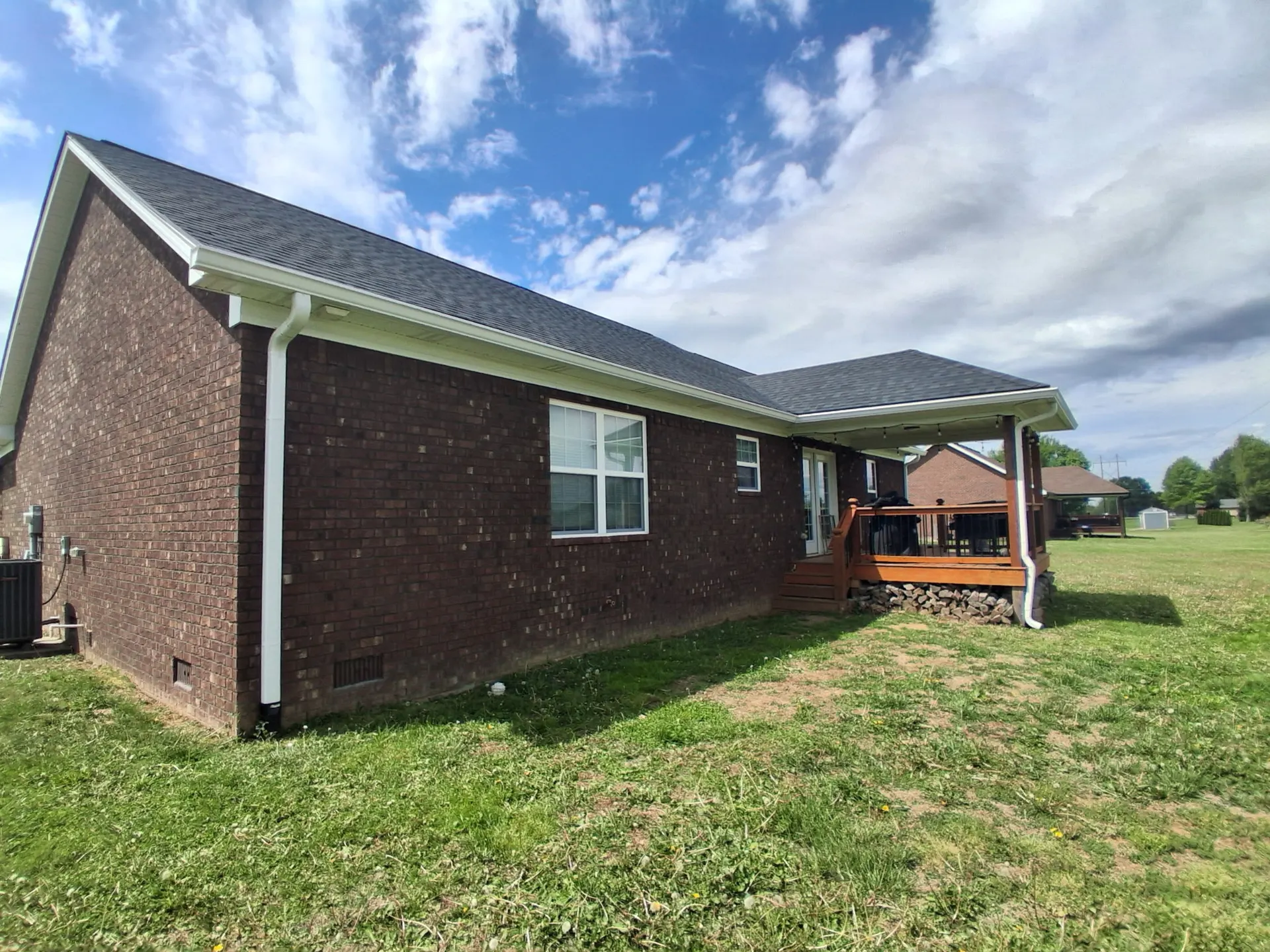 TNT Roofing seamless white gutter and downspout installation on a brick home