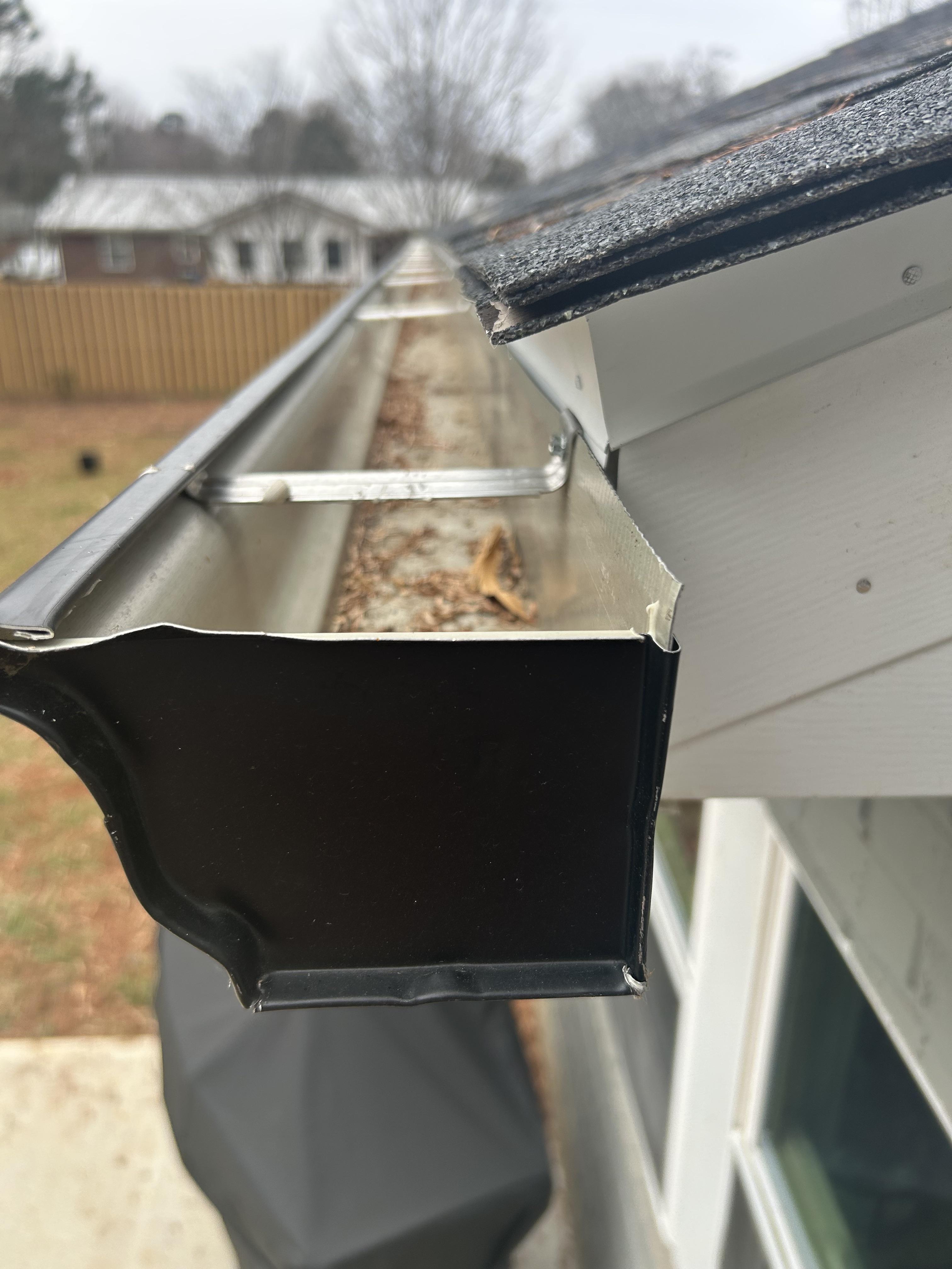 Real TNT Roofing project photo: clogged gutter filled with leaves and debris, showing the need for gutter cleaning and guard installation