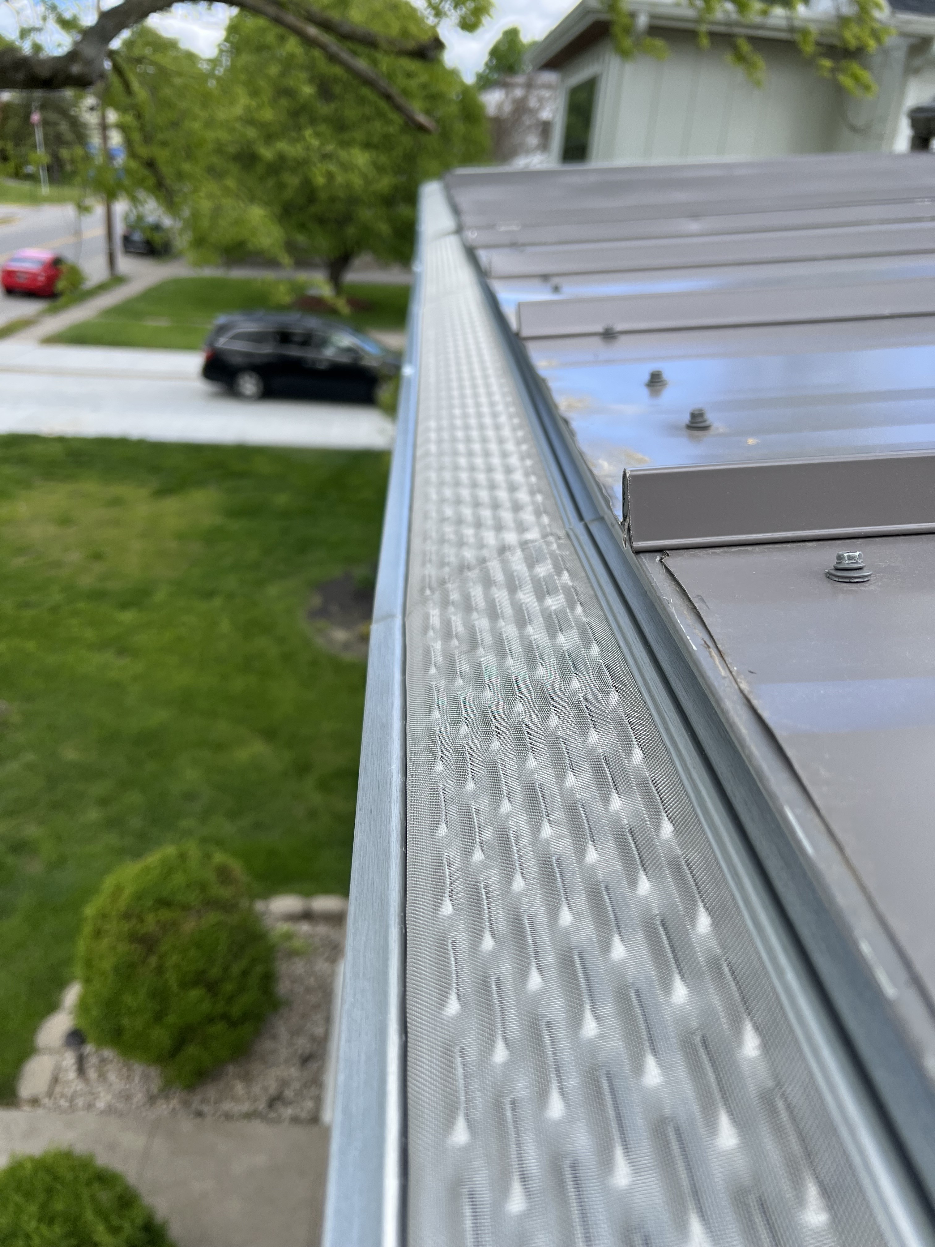 Real TNT Roofing project: micro-mesh gutter guard installed along a metal roofline, blocking debris while allowing water flow