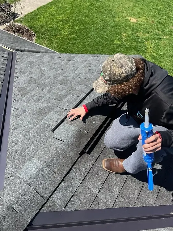 TNT Roofing project: worker applying sealant with a caulking gun during shingle roof repair