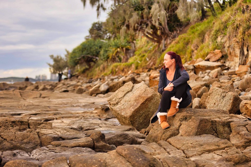 Jodi sitting on rocks by the beach, looking out to sea