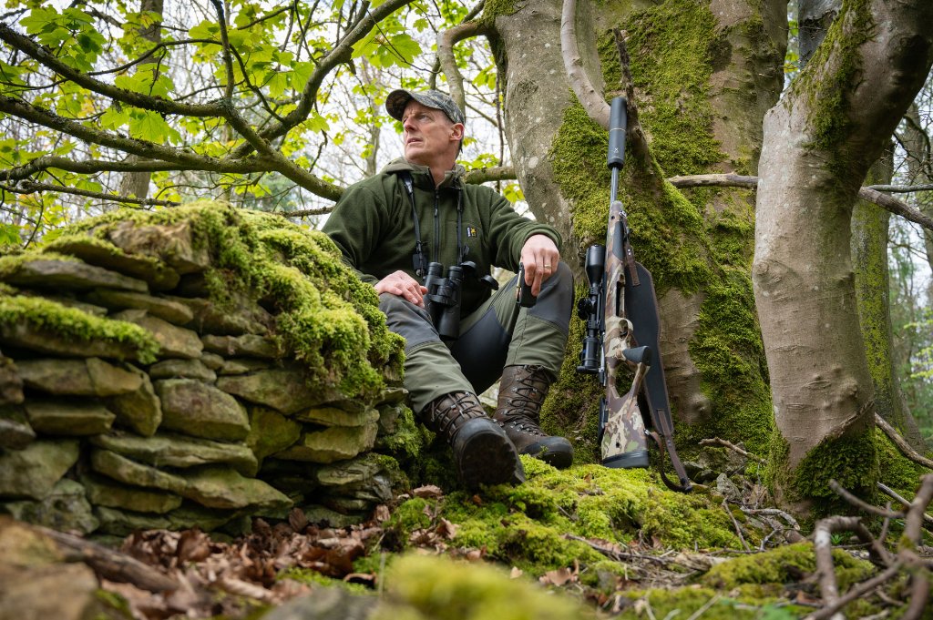Paul Childerley deer stalking — resting against moss-covered stone wall in British woodland