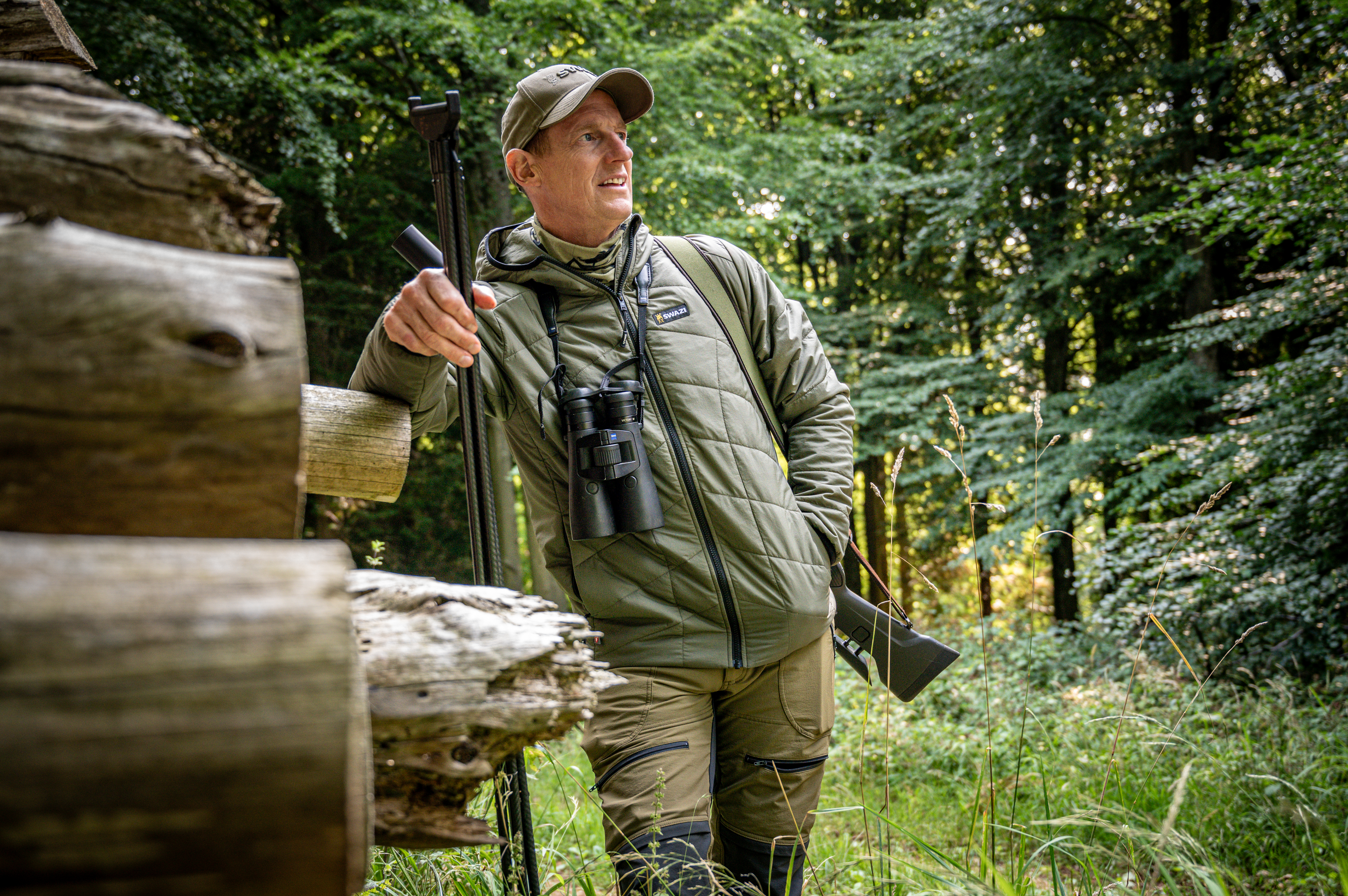 Paul Childerley deer stalking in summer woodland wearing Swazi clothing with Zeiss binoculars
