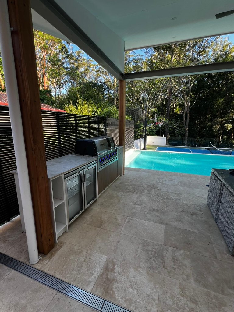 Outdoor kitchen under covered patio beside swimming pool
