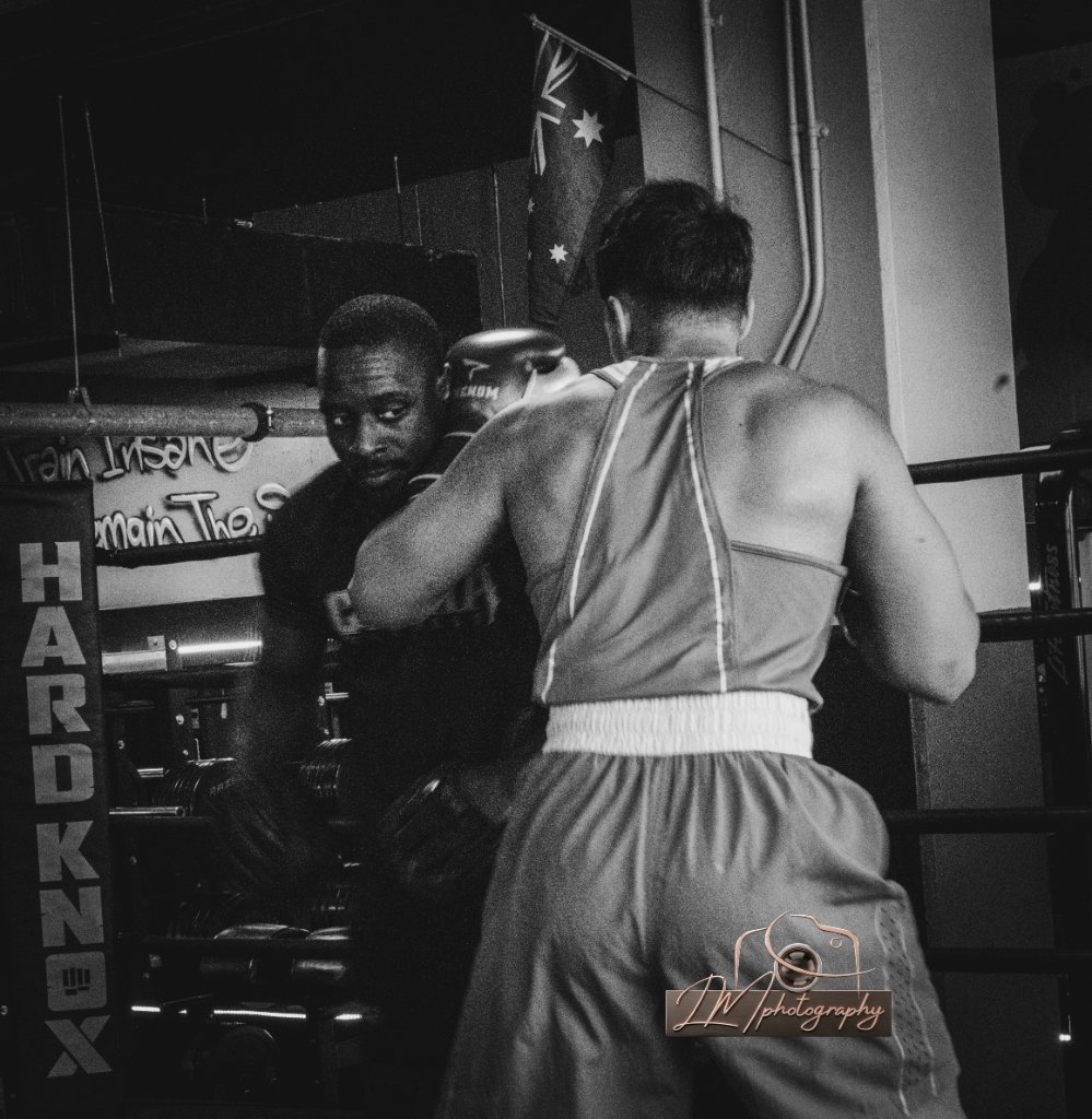 Two boxers sparring in a gym ring with HARD KNOX lettering