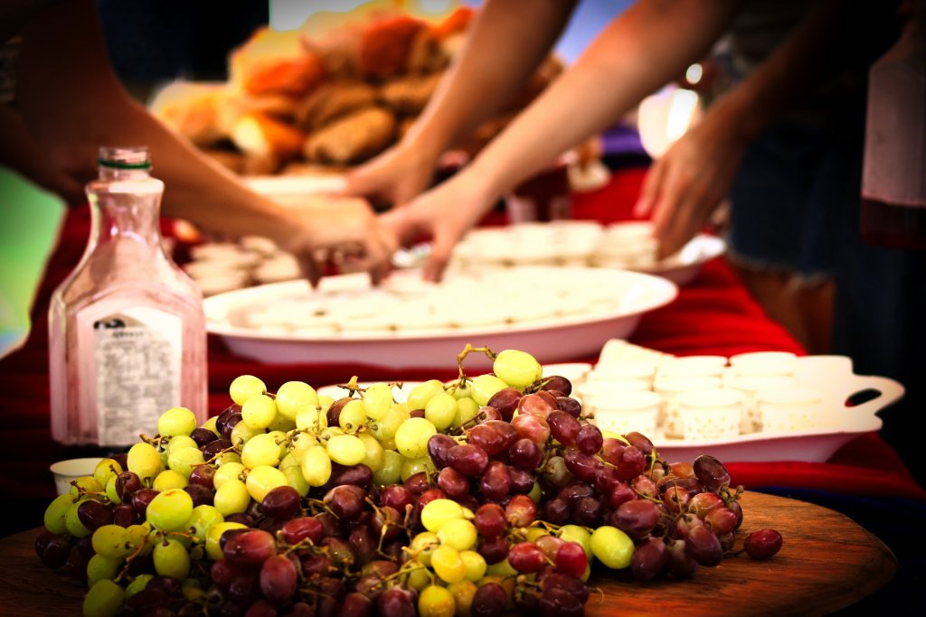 Festive outdoor gathering with fresh grapes and refreshments, guests mingling in warm lighting
