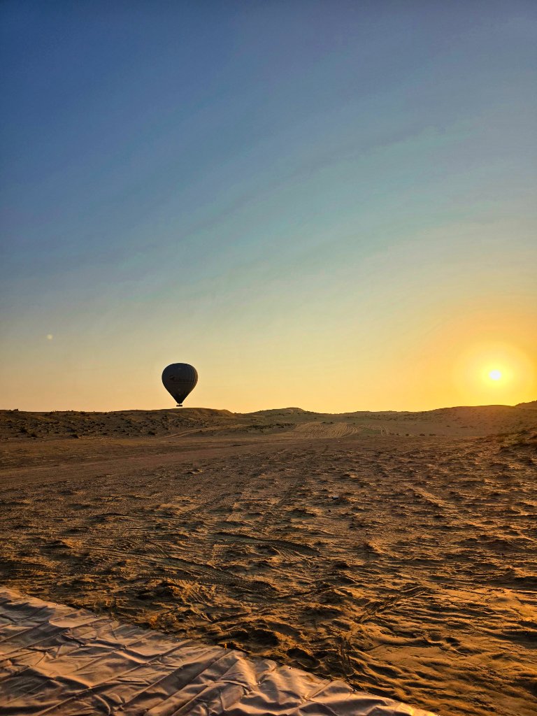 Hot air balloon at sunrise over desert landscape