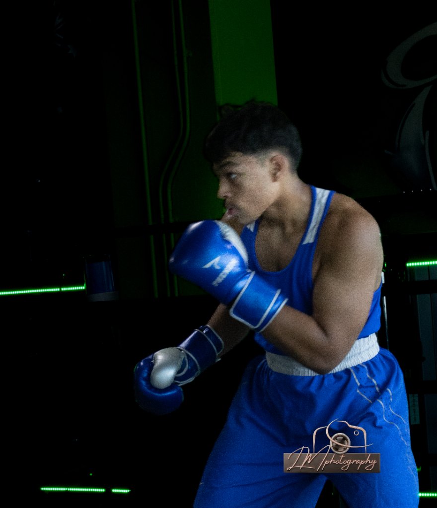 Boxer in blue Nike gear and Phenom gloves in a dark gym setting