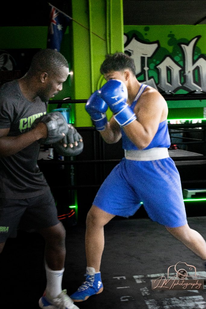 Boxer sparring with coach using focus mitts in a gym with green lighting